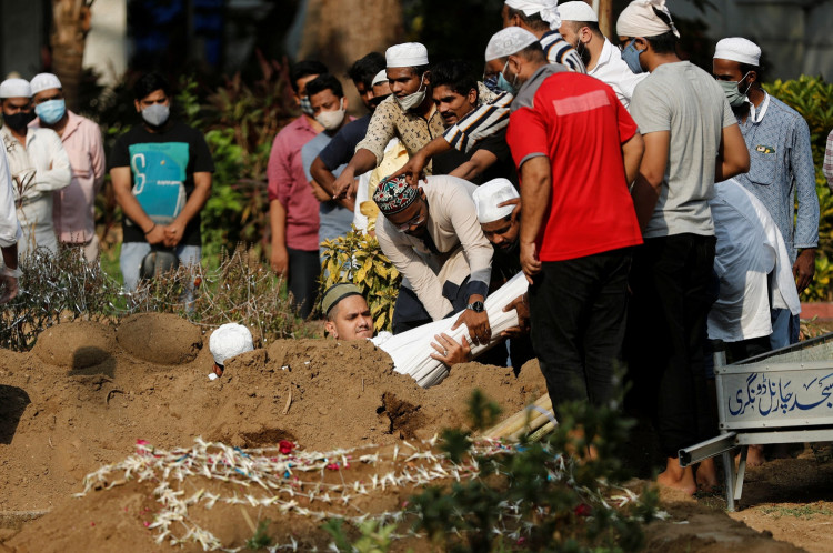 Relatives lower the body of a person who died from the coronavirus disease (COVID-19) at a graveyard in Mumbai