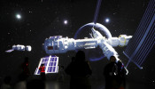 FILE PHOTO: Visitors stand near a giant screen displaying the images of the Tianhe space station 