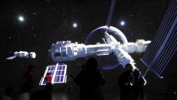 FILE PHOTO: Visitors stand near a giant screen displaying the images of the Tianhe space station 