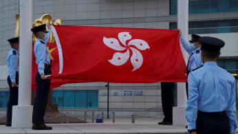Police officers fold Chinese and Hong Kong flags at a flag-lowering ceremony on the Golden Bauhinia Square in Hong Kong, China March 30, 2021. 