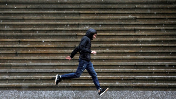 A person runs along Wall Street as heavy rain and hail falls in New York City.