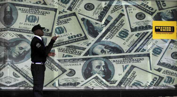 A security guard walks past a montage of old U.S. dollar bills outside a currency exchange.