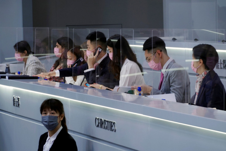 Employees of Christie's auction house speak to people on the phones as they bid for Sakura Diamond, a 15.81 carat purple pink diamond ring, in Hong Kong, China May 23, 2021. 