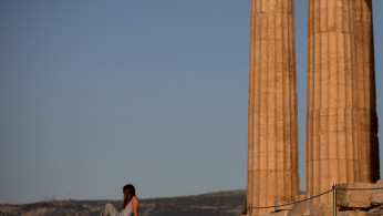 FILE PHOTO: A woman rests on a new cement walkway next to the Parthenon temple, built to improve access for people with disabilities atop the Acropolis hill, in Athens, Greece, June 8, 2021. 