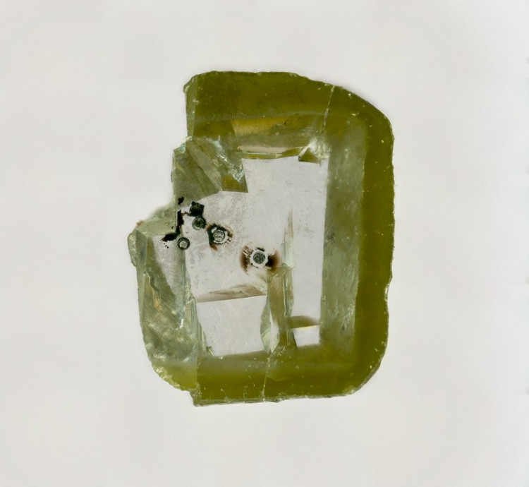 A diamond holding tiny black specks of davemaoite, a mineral formed at high temperature and pressure in the deep Earth.