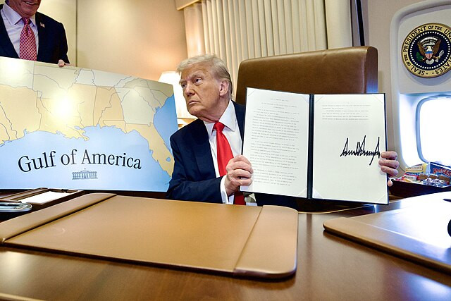 President Donald Trump on Air Force One poses next to a map of the Gulf of America during a flight to New Orleans on February 9, 2025.