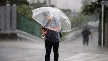 Passersby using umbrella struggles against a heavy rain and wind as Typhoon Jongdari approaches Japan's mainland in Tokyo