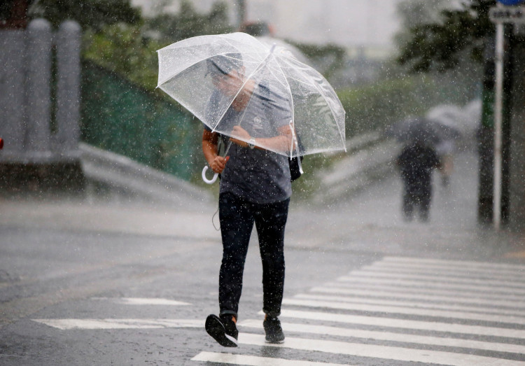 Passersby using umbrella struggles against a heavy rain and wind as Typhoon Jongdari approaches Japan's mainland in Tokyo