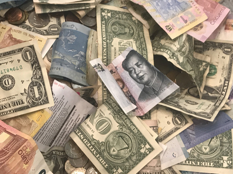 .S. dollars and other world currencies lie in a charity receptacle at Pearson international airport in Toronto