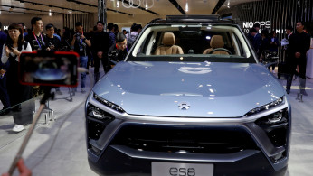 Visitors check NIO ES8 displayed during a media preview of the Auto China 2018 motor show in Beijing