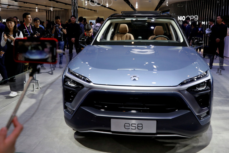 Visitors check NIO ES8 displayed during a media preview of the Auto China 2018 motor show in Beijing