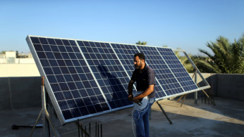 Palestinian man installs solar panels on a house rooftop in Khan Younis in the southern Gaza Strip