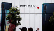People walk past an advertisement for Huawei outside an electronic store in Tokyo