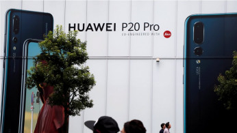 People walk past an advertisement for Huawei outside an electronic store in Tokyo