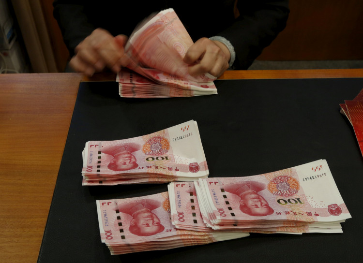 A staffer poses with 2015 edition of the 100 renminbi notes at the Bank of China Tower in Hong Kong