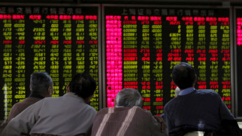 Men look at an electronic board showing stock information at a brokerage house in Beijing