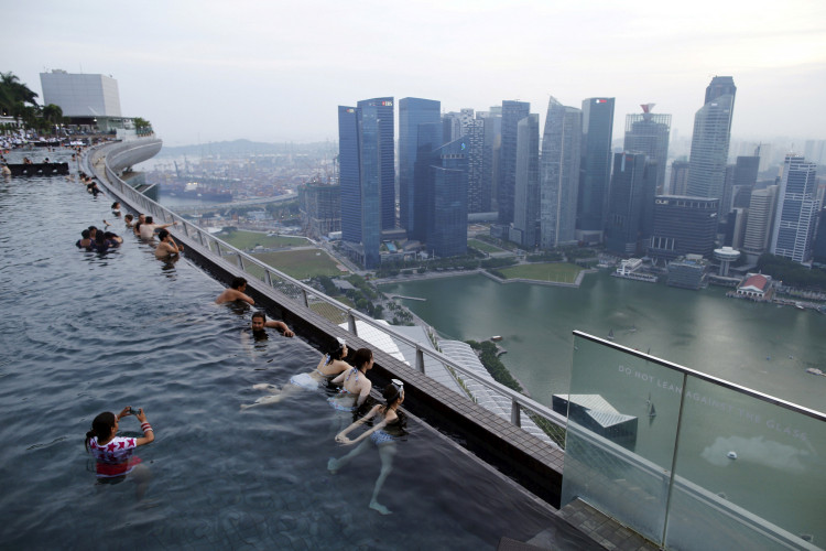 Tourists look out into the skyline of the city from an infinity pool atop the 57-storey Marina Bay Sands hotel in Singapore