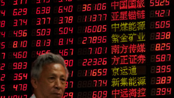 An investor stands in front of an electronic board showing stock information at a brokerage house in Shanghai