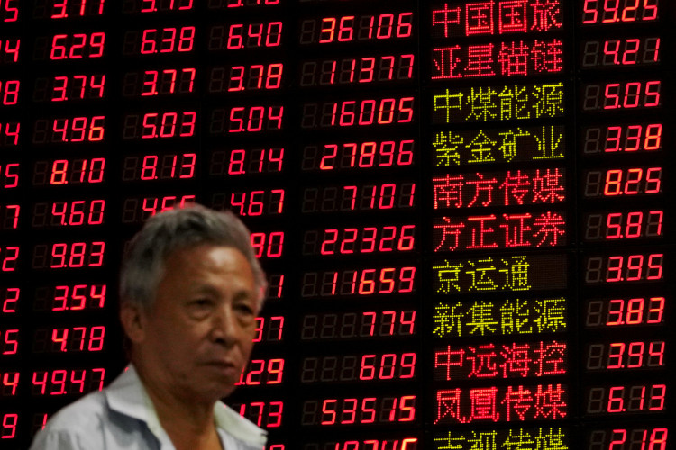 An investor stands in front of an electronic board showing stock information at a brokerage house in Shanghai