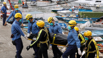 Firemen carry a covered body near the Sai Kung Hoi Pong Street waterfront