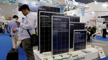 A visitor stands next to solar panels during the China Import and Export Fair, also known as Canton Fair