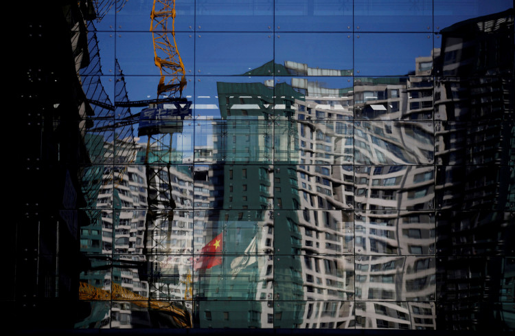 A construction site and a residential building are reflected on the glass wall of a building