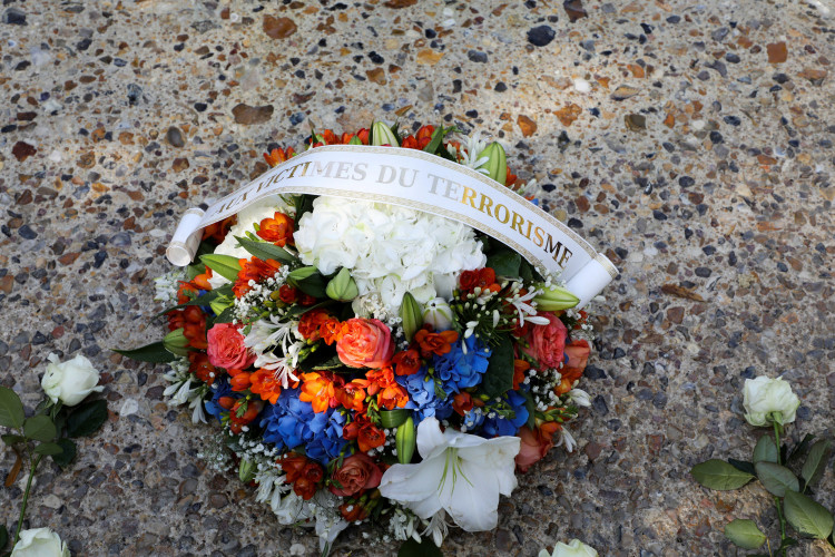 A flowers bouquet reading "for the victims of terrorism" lays in front of a memorial fountain during a national ceremony to pay tribute to the victims of militant attacks, in Paris
