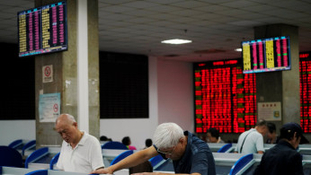 Investors look at computer screens showing stock information at a brokerage house in Shanghai