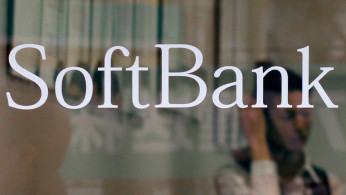 An employee works behind a logo of Softbank Corp at its branch in Tokyo