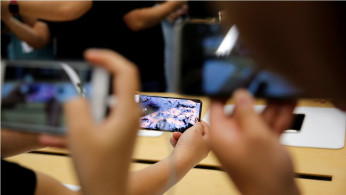 People handle the new Apple iPhone XS and iPhone XS Max during a media tour at an Apple office in Shanghai