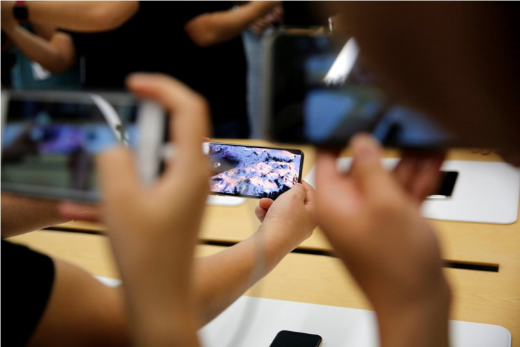 People handle the new Apple iPhone XS and iPhone XS Max during a media tour at an Apple office in Shanghai