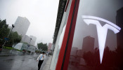 FILE PHOTO:  A man walks near a logo of Tesla outside its China headquarters at China Central Mall in Beijing, China July 11, 2018