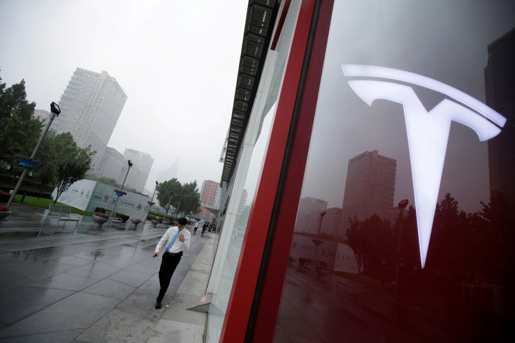 FILE PHOTO:  A man walks near a logo of Tesla outside its China headquarters at China Central Mall in Beijing, China July 11, 2018