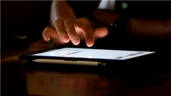 A man uses an iPad device in a coffee shop in Hanoi