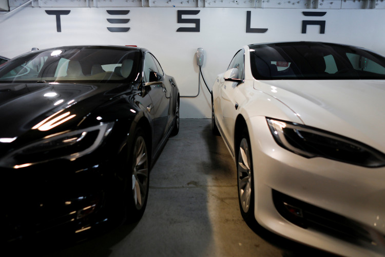 Two Tesla Model 3 vehicles are shown charging in an underground parking lot next to a Tesla store in San Diego