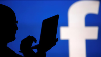 A man is silhouetted against a video screen with an Facebook logo in this photo illustration in Zenica