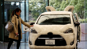 A woman touches Toyota's vehicle decorated as shape of dog at its headquarters in Tokyo