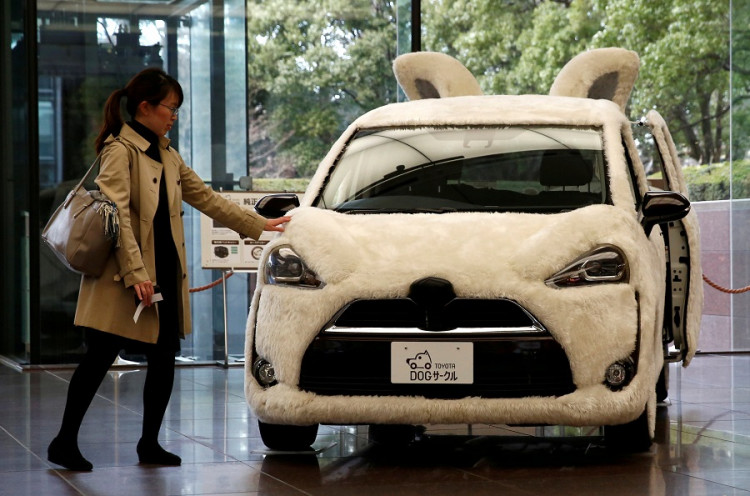 A woman touches Toyota's vehicle decorated as shape of dog at its headquarters in Tokyo