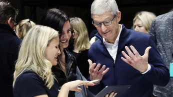 Apple CEO Tim Cook tries out the new iPad Pro as singer Lana Del Rey (middle) looks on during an Apple launch event in the Brooklyn borough of New York