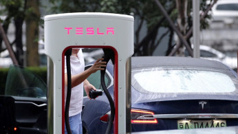 A man finishes charging his Tesla car at a charging point outside Tesla China headquarters in Beijing