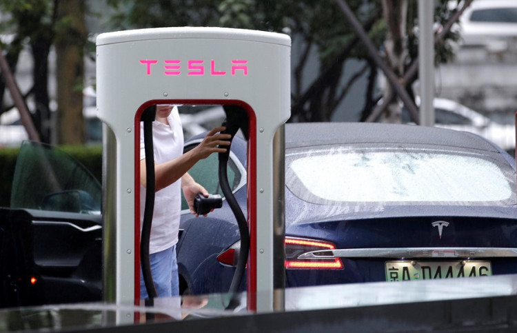 A man finishes charging his Tesla car at a charging point outside Tesla China headquarters in Beijing