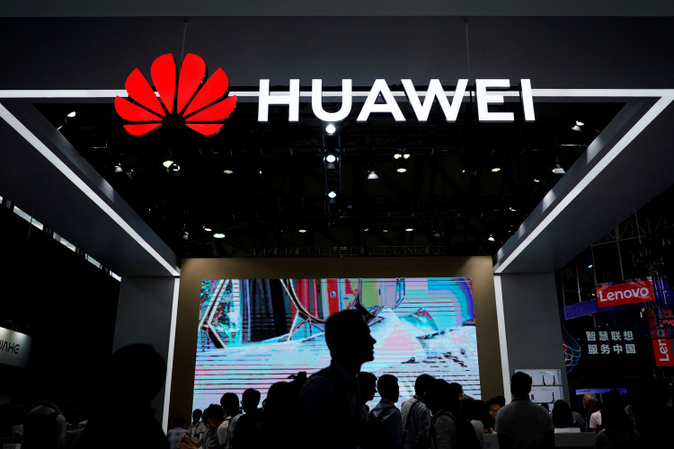 People walk past a sign board of Huawei at CES (Consumer Electronics Show) Asia 2018 in Shanghai
