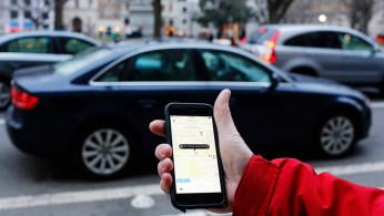 An UBER application is shown as cars drive by in Washington, DC.