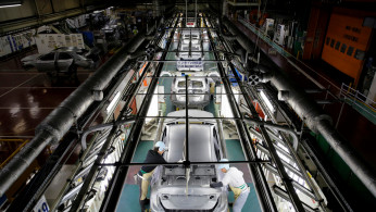 Employees work on an assembly line of the Toyota Motor Corp's Prius hybrid car at the Tsutsumi plant in Toyota