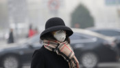 A woman wearing a mask walks on a road as heavy smog blankets China's capital Beijing