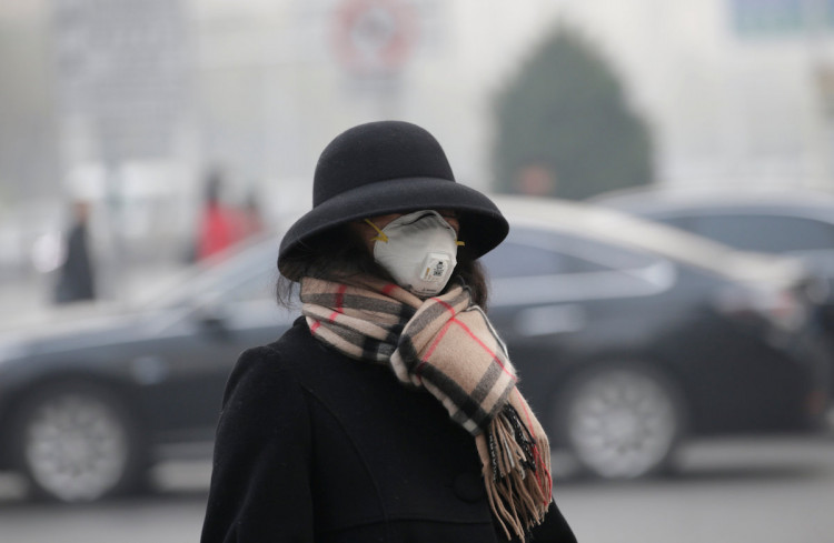 A woman wearing a mask walks on a road as heavy smog blankets China's capital Beijing