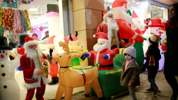 Iraqi children walk next to a store selling Christmas decorations in Baghdad