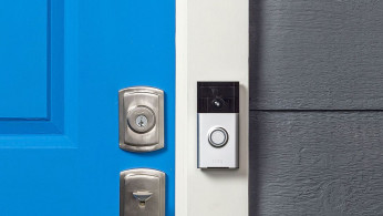 The Ring video doorbell, mounted next to the front door of a house.