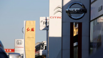 People walk near the showrooms of Chinese and foreign car dealerships in Beijing