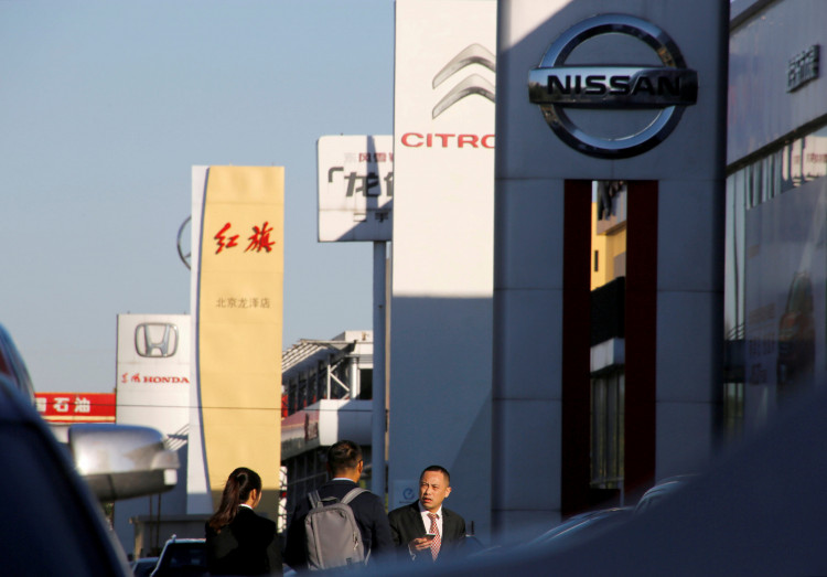 People walk near the showrooms of Chinese and foreign car dealerships in Beijing